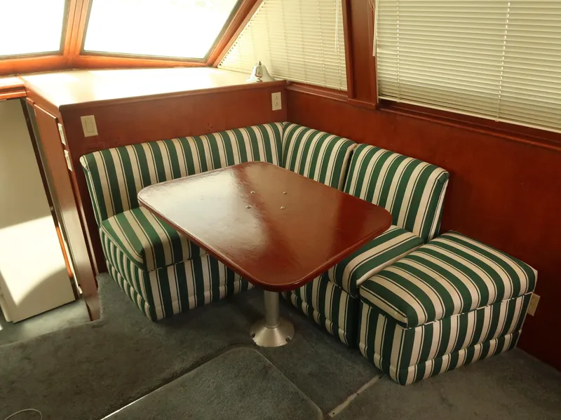 Slide: The Image of Interior of 1994 Hatteras 42 Cockpit Motor Yacht with striped seating and wooden table. - 18