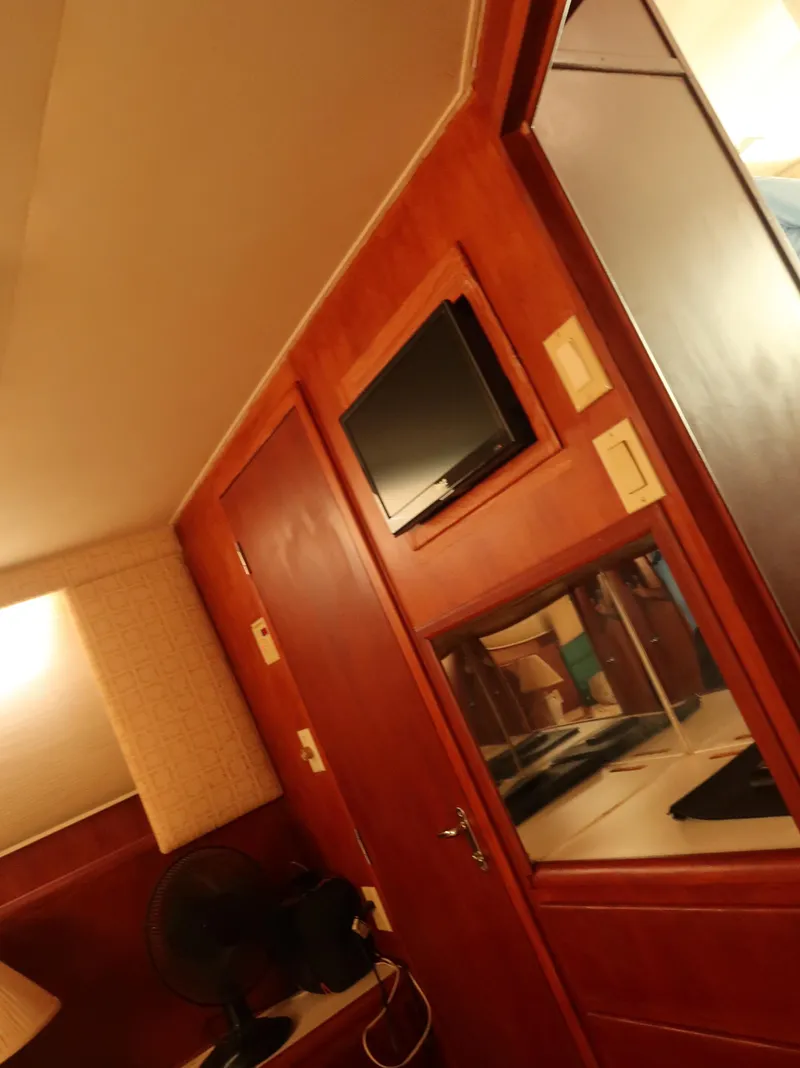 Slide: The Image of 1994 Hatteras 42 Cockpit Motor Yacht interior with wood paneling and mounted TV. - 37