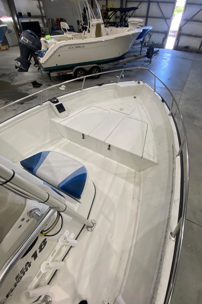 Slide: The Image of 2000 Triton 18 Sea Flight boat interior in a garage, featuring seating and storage. - 8