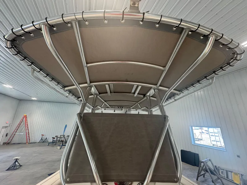 Slide: The Image of 2011 Edgewater 228CC boat with a sturdy T-top frame in a spacious indoor setting. - 10