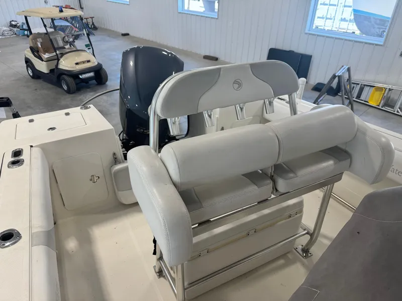 Slide: The Image of 2011 Edgewater 228CC boat interior with seating and motor, parked indoors near a golf cart. - 11