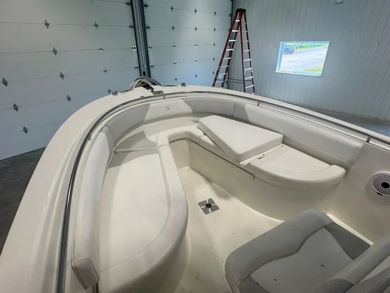Slide: The Image of 2011 Edgewater 228CC boat interior with white seating in a garage. - 8