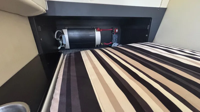 Slide: The Image of Interior view of a 2014 Monterey 328 Super Sport boat, featuring a striped cushion and storage compartment. - 26