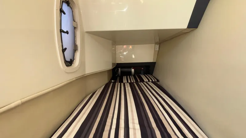 Slide: The Image of 2014 Monterey 328 Super Sport cabin interior with striped bedding and porthole window. - 28