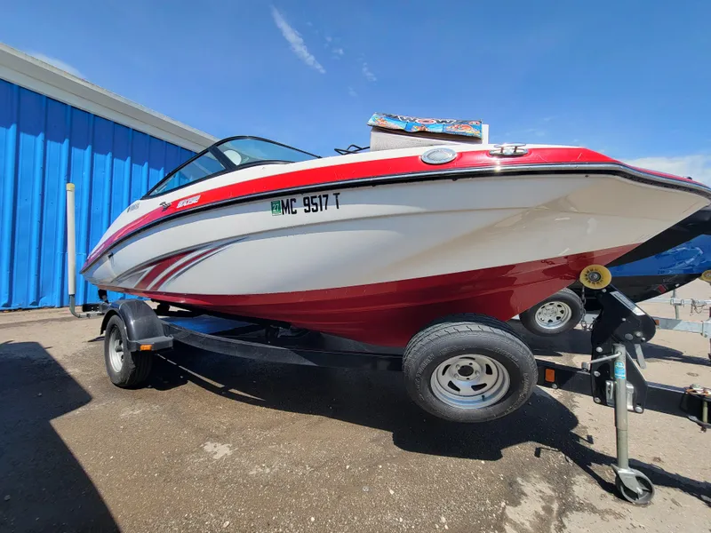The Image of 2016 Yamaha Boats SX192 on trailer, red and white, parked outdoors. - 0