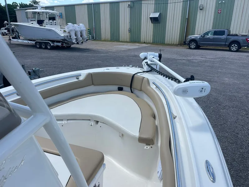 Slide: The Image of 2019 Pioneer 202 Sportfish boat with tan seating, parked near a warehouse. - 10