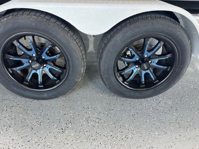 Slide: The Image of 2024 Axis T250 wheels with black and blue rims on a speckled garage floor. - 3