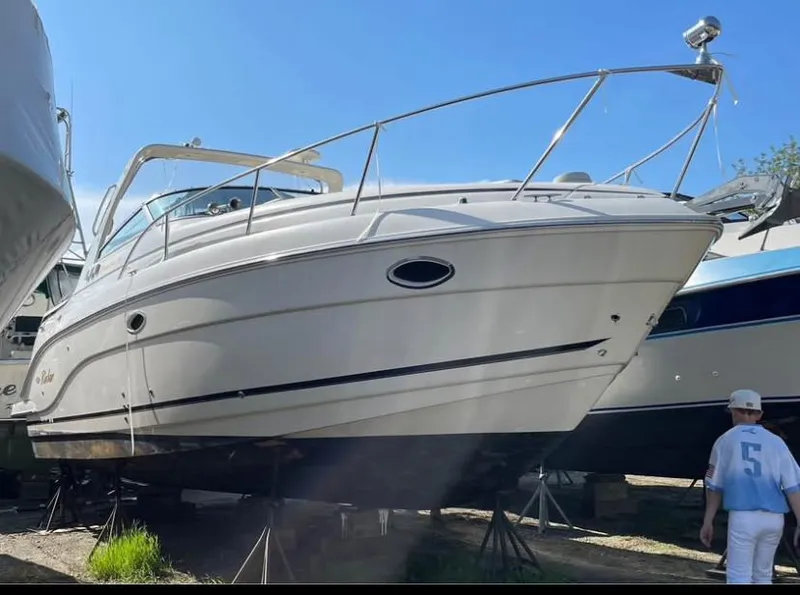 Slide: The Image of 2006 Rinker 300 Fiesta Vee boat on stands, sunny day, person nearby. - 2