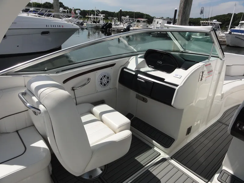 Slide: The Image of 2009 Sea Ray 250 SLX boat interior with white seating and dashboard, docked at marina. - 10