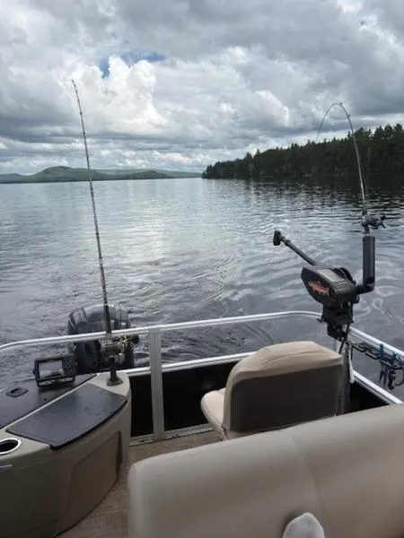 Slide: The Image of Pontoon boat on a serene lake, equipped for fishing, under a cloudy sky. - 10
