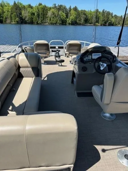 Slide: The Image of 2021 Sun Tracker FB 20 DLX pontoon boat interior with beige seating, steering console, and lake view. - 4