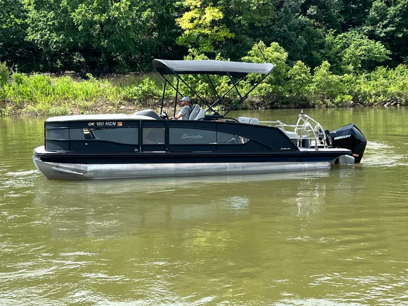 Slide: The Image of 2024 Barletta Lusso 23UC pontoon boat cruising on a calm river with lush greenery. - 10