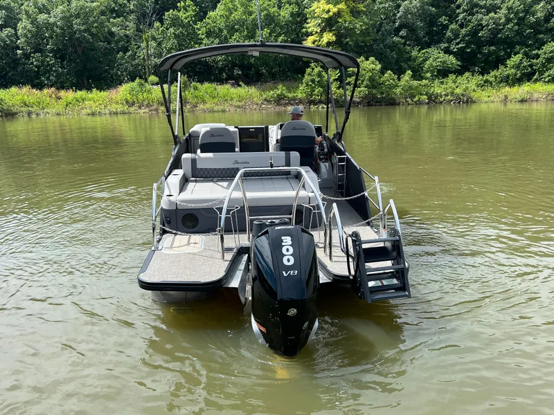 Slide: The Image of 2024 Barletta Lusso 23UC pontoon boat on a calm lake, featuring a powerful 300 V8 engine. - 2