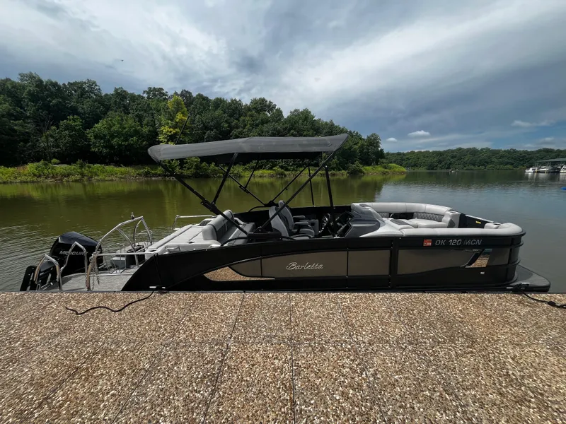 Slide: The Image of 2024 Barletta Lusso 23UC pontoon boat docked by a scenic lake. - 7