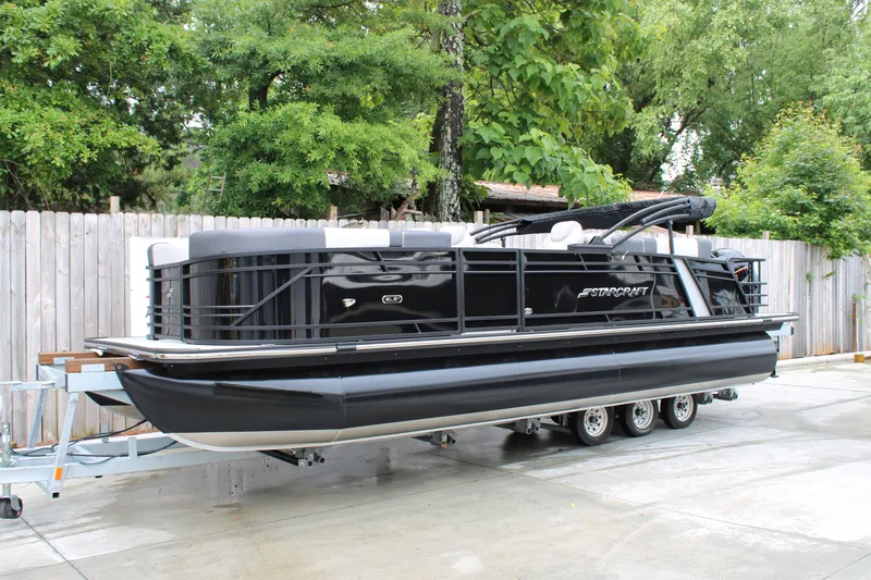 The Image of 2025 Starcraft SLS 3 pontoon boat on trailer, parked outdoors. - 0