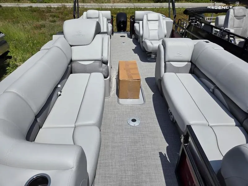 Slide: The Image of 2025 Regency 230 DL3 pontoon boat interior with gray seating and a cardboard box on the floor. - 14