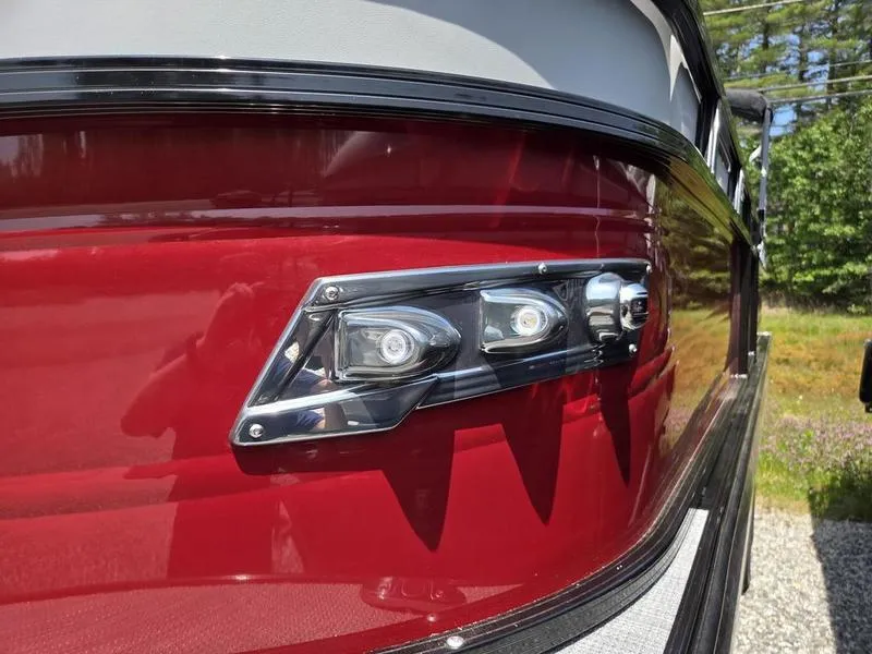Slide: The Image of Close-up of 2025 Regency 230 DL3 boat's sleek red exterior with modern LED lights. - 4