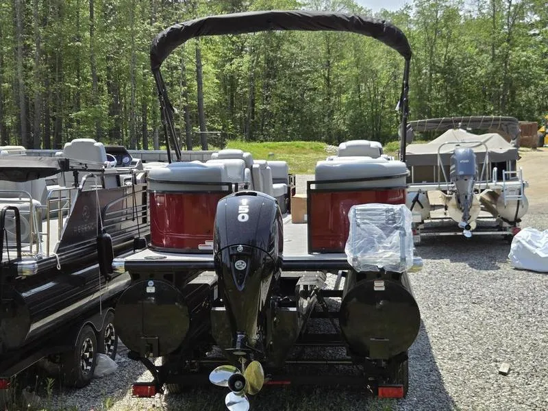 Slide: The Image of 2025 Regency 230 DL3 pontoon boat with outboard motor, parked on gravel lot. - 7