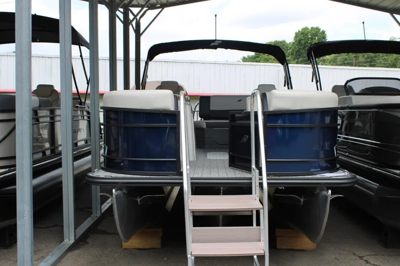 Slide: The Image of 2025 Starcraft EXS 3 DL pontoon boat in storage, featuring blue exterior and covered dock. - 5