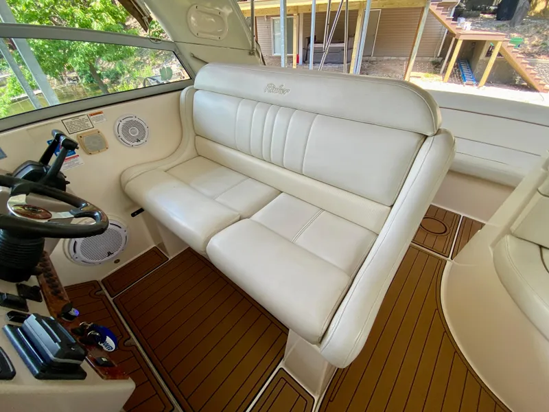 Slide: The Image of 2006 Rinker 360 Fiesta Vee boat interior with white seating and wooden flooring. - 14