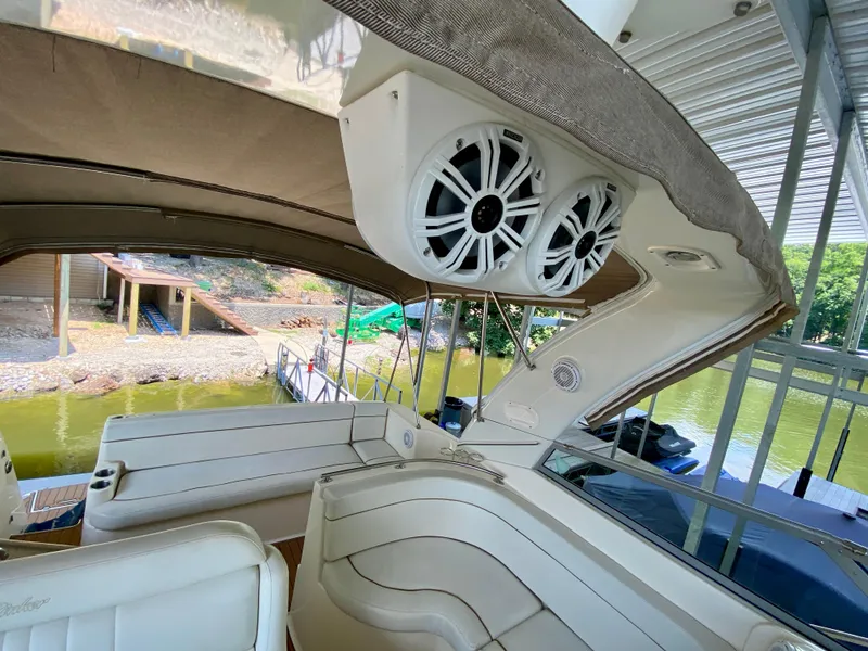 Slide: The Image of 2006 Rinker 360 Fiesta Vee boat interior with speakers and seating, docked by a lake. - 22