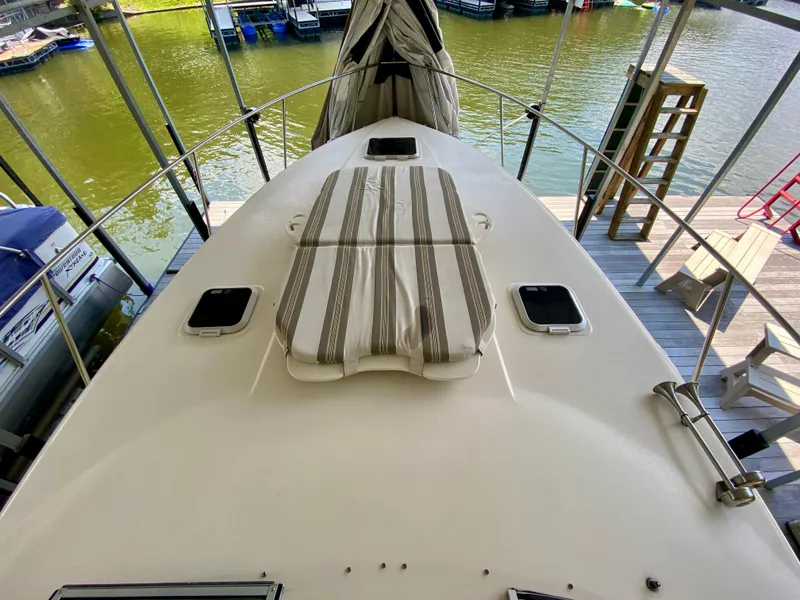 Slide: The Image of 2006 Rinker 360 Fiesta Vee boat deck with striped cushion, docked by the water. - 24