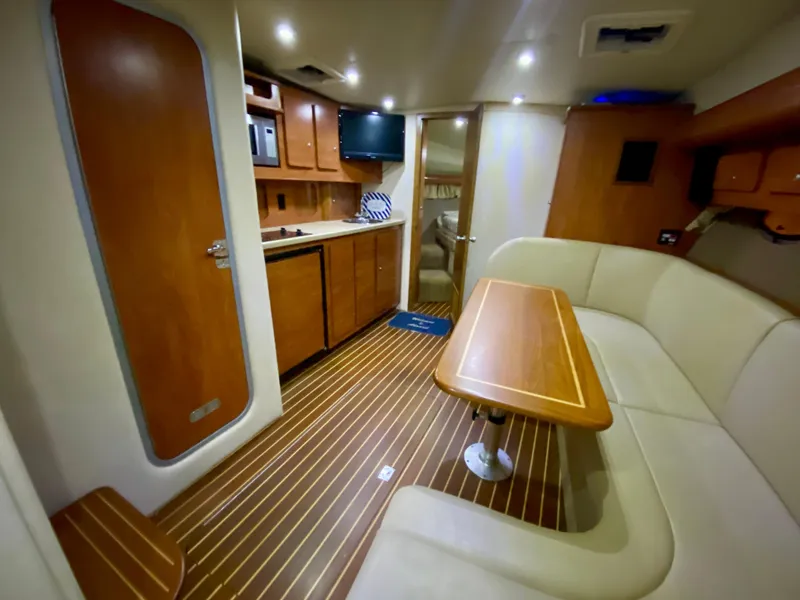 Slide: The Image of 2006 Rinker 360 Fiesta Vee yacht interior with wood flooring, kitchenette, and seating area. - 26
