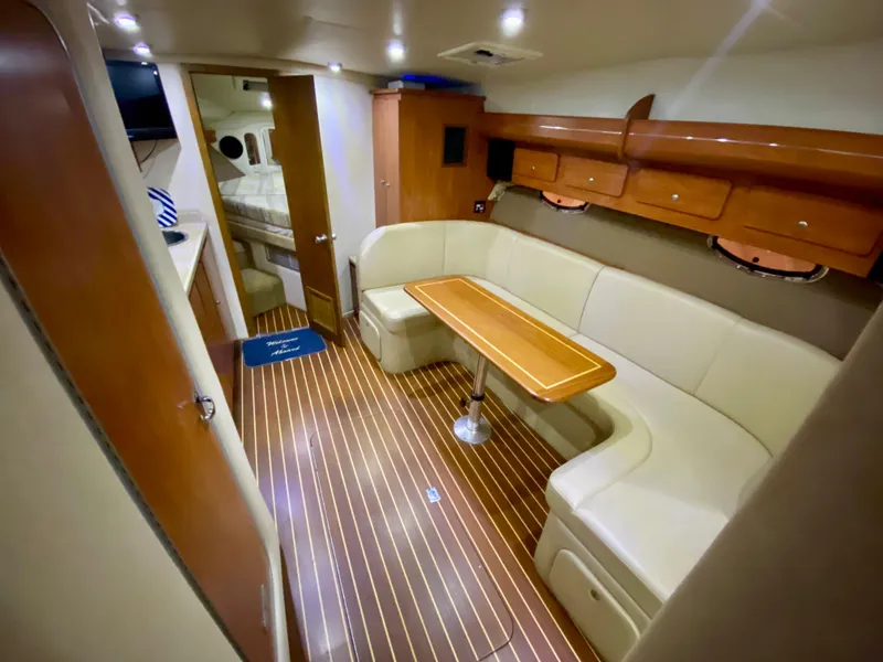 Slide: The Image of 2006 Rinker 360 Fiesta Vee interior with wood flooring, beige seating, and dining table. - 27