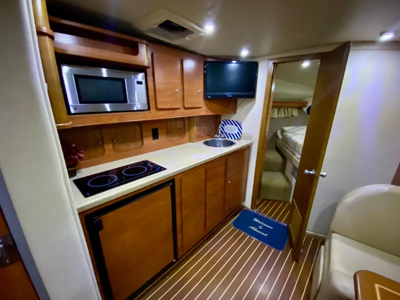 Slide: The Image of 2006 Rinker 360 Fiesta Vee yacht interior with kitchenette, microwave, and cozy cabin. - 28