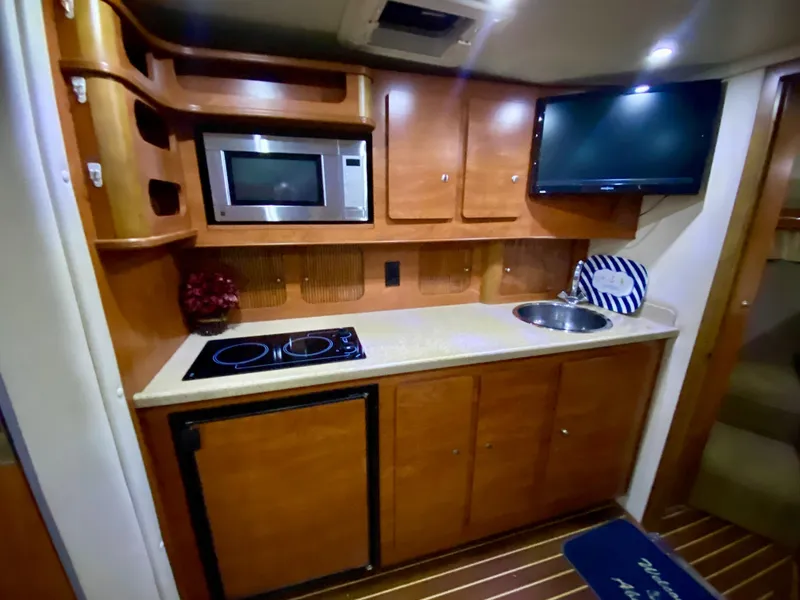 Slide: The Image of 2006 Rinker 360 Fiesta Vee yacht kitchen with microwave, stove, sink, and TV. - 29