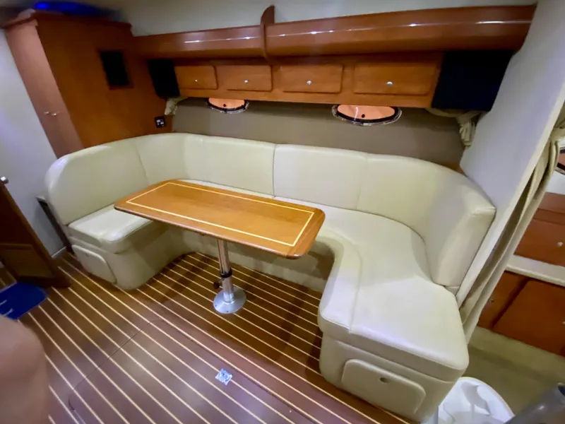 Slide: The Image of 2006 Rinker 360 Fiesta Vee interior with beige seating and wooden table. - 30
