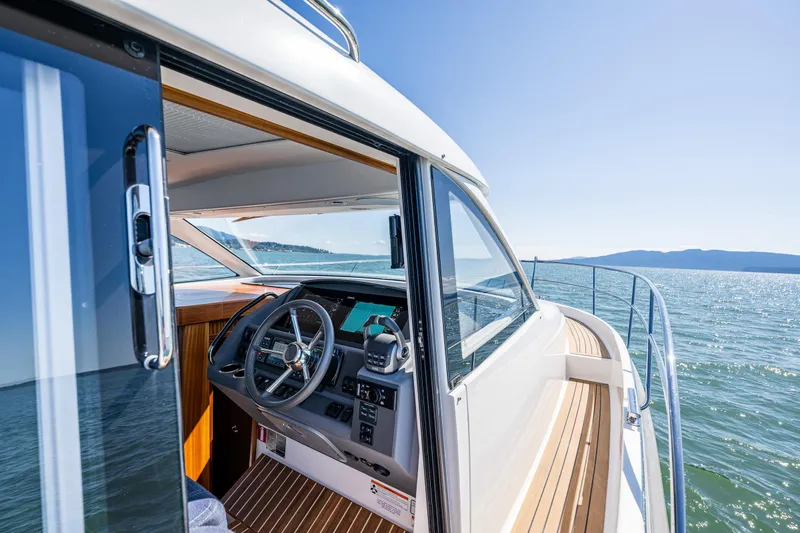 Slide: The Image of 2021 Nimbus 405 Coupé #88 yacht interior with steering wheel, cruising on open water. - 11