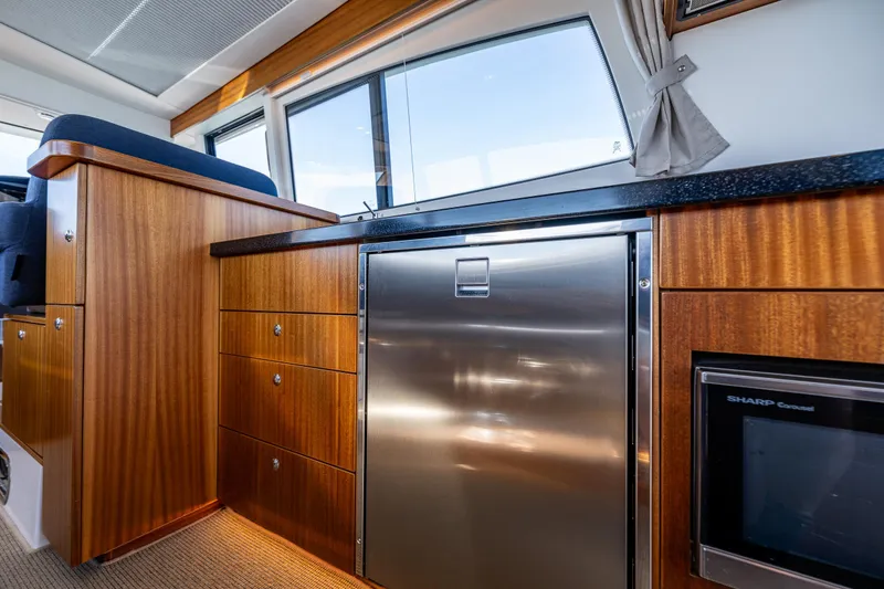 Slide: The Image of Luxurious interior of 2021 Nimbus 405 Coupé yacht with wood cabinetry and stainless steel appliances. - 23