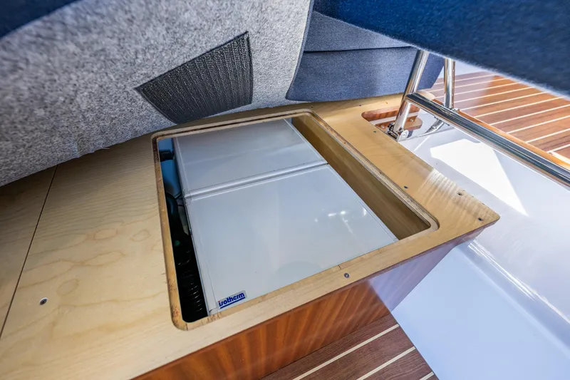 Slide: The Image of Under-seat storage compartment in a 2021 Nimbus 405 Coupé boat, featuring a built-in refrigerator. - 24