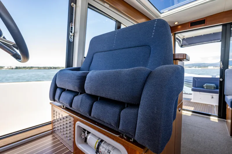 Slide: The Image of Blue captain's chair in 2021 Nimbus 405 Coupé yacht interior, overlooking water. - 27
