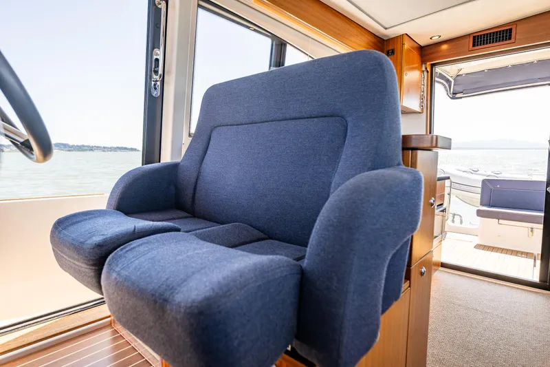 Slide: The Image of Blue captain's chair inside 2021 Nimbus 405 Coupé yacht, with scenic water view. - 28