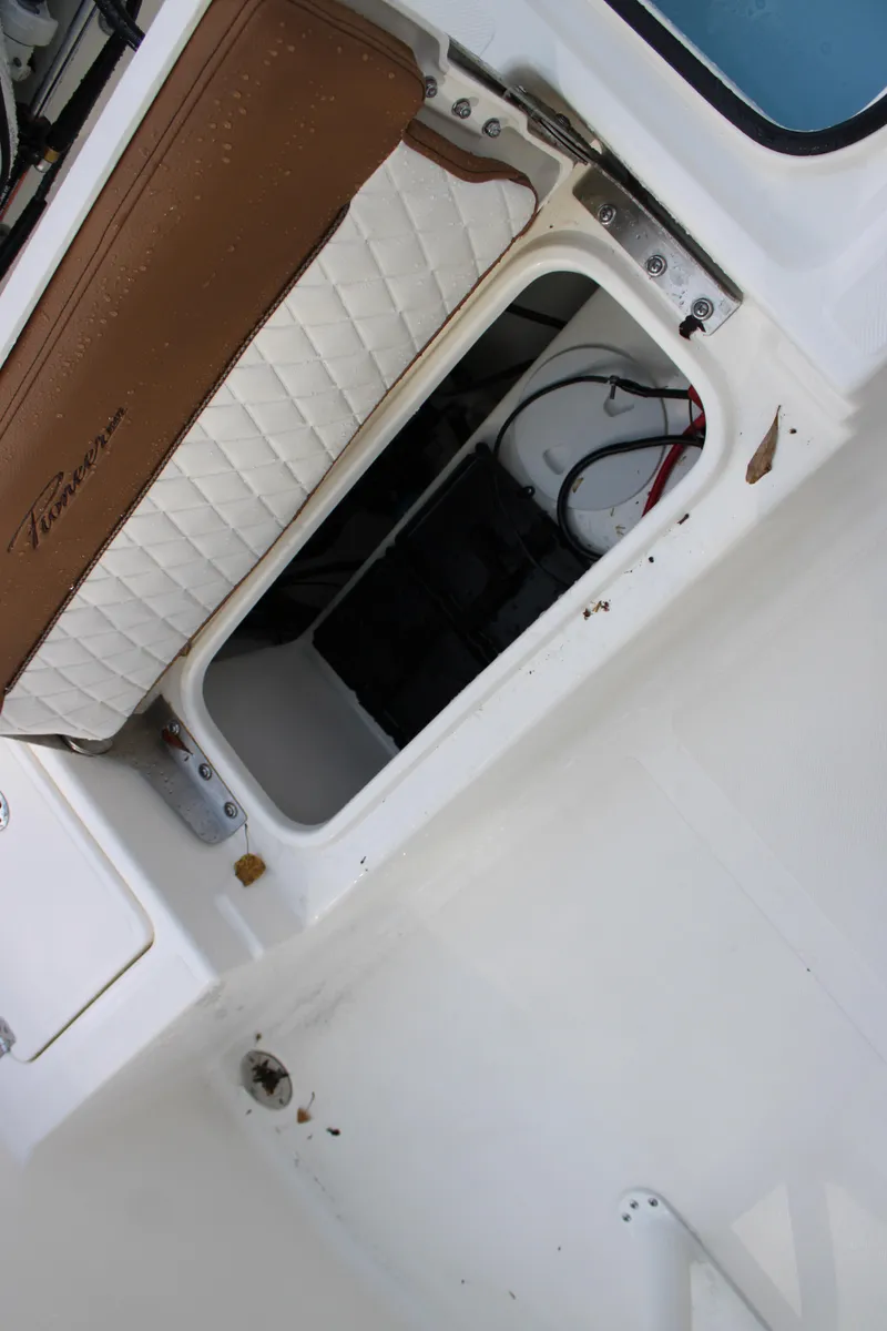 Slide: The Image of 2025 Pioneer 220 Bay Sport boat storage compartment with brown and white cushioned seat. - 18