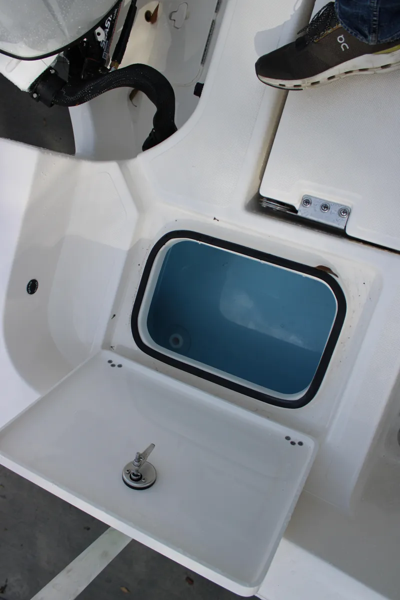 Slide: The Image of 2025 Pioneer 220 Bay Sport boat interior with open storage compartment and footrest. - 19