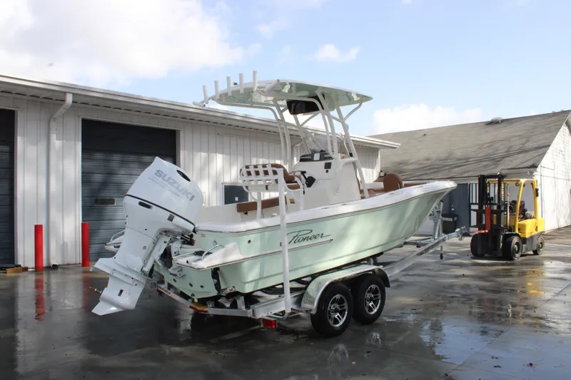 Slide: The Image of 2025 Pioneer 220 Bay Sport boat on trailer near warehouse, featuring Suzuki outboard motor. - 3