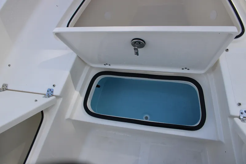 Slide: The Image of 2025 Pioneer 220 Bay Sport boat storage compartment with open lid and blue interior. - 9