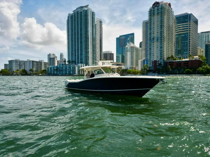Slide: The Image of 2021 Scout 380 LXF boat on water with city skyline in background. - 10