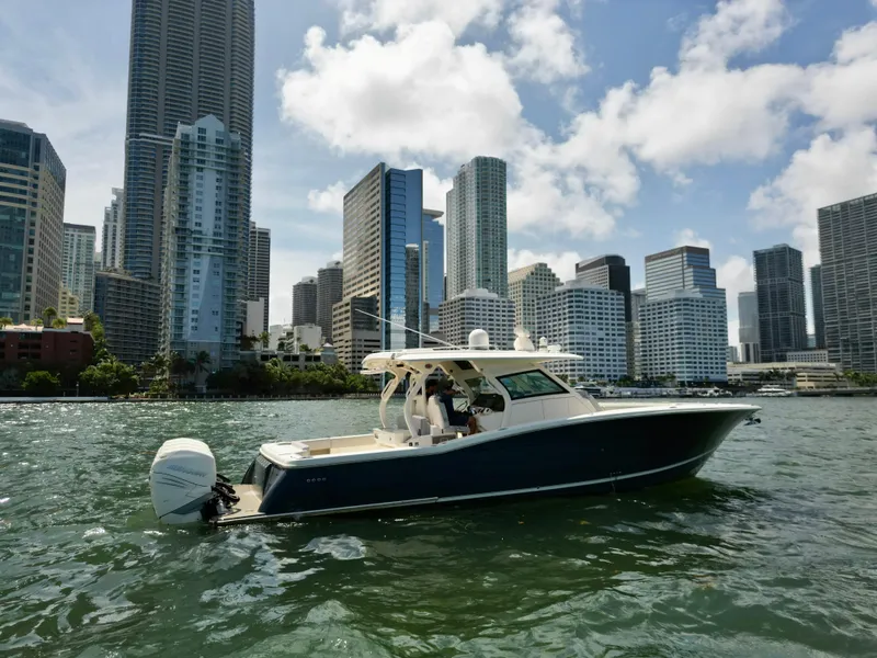 Slide: The Image of 2021 Scout 380 LXF boat cruising near city skyline on a sunny day. - 12
