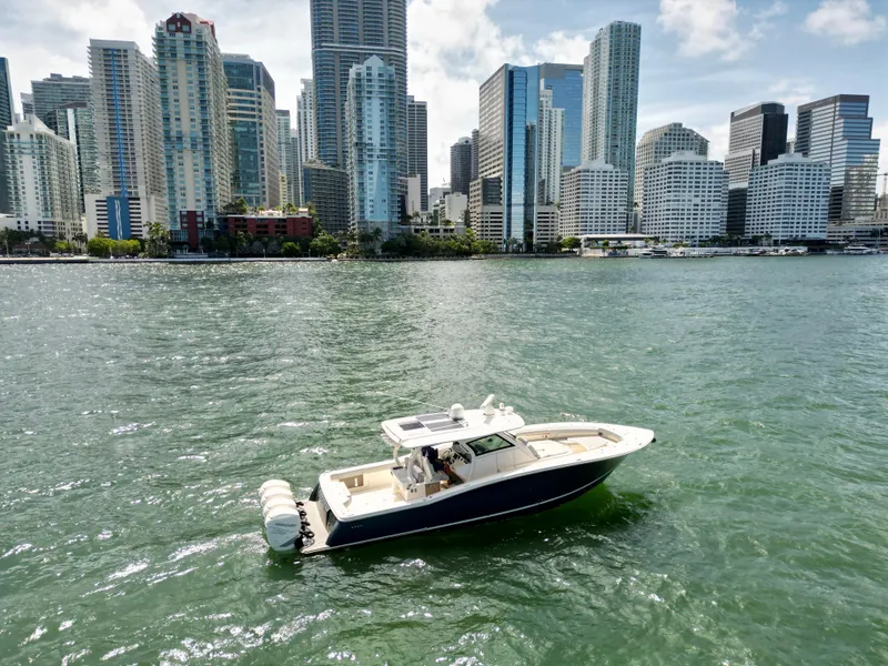 Slide: The Image of 2021 Scout 380 LXF boat cruising near city skyline on a sunny day. - 16