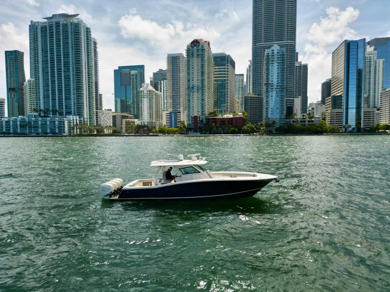 Slide: The Image of 2021 Scout 380 LXF boat cruising near city skyline. - 2