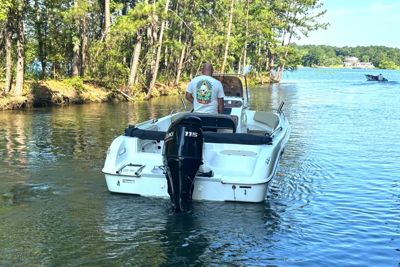 Slide: The Image of A 2019 Key Largo 2000 boat navigating a serene, tree-lined waterway. - 11