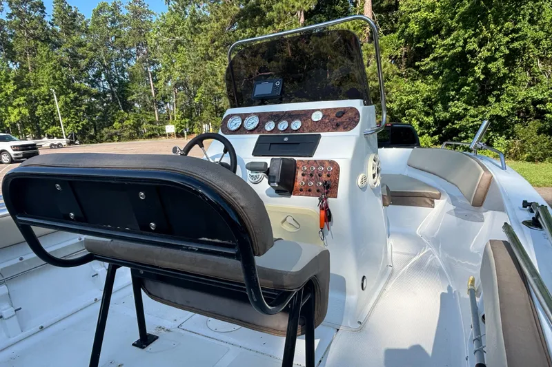 Slide: The Image of 2019 Key Largo 2000 boat interior with steering console and seating, surrounded by lush greenery. - 6