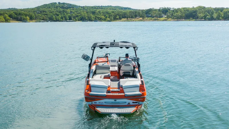 Slide: The Image of 2018 Malibu Wakesetter 24 MXZ on a serene lake, surrounded by lush greenery. - 4
