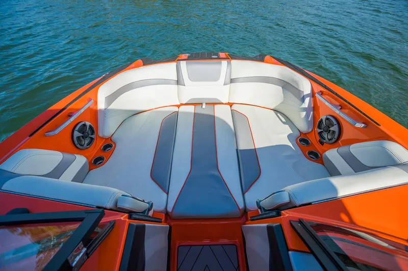 Slide: The Image of 2018 Malibu Wakesetter 24 MXZ boat interior with orange and gray seating on water. - 5