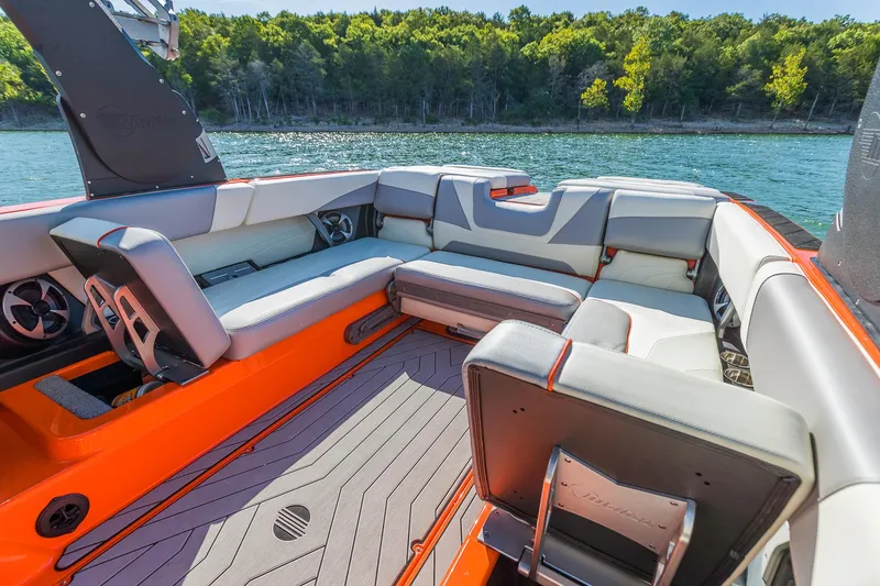 Slide: The Image of 2018 Malibu Wakesetter 24 MXZ interior with orange accents, spacious seating, and lake view. - 6