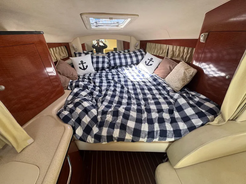 Slide: The Image of Cozy cabin interior of 2005 Sea Ray 300 Sundancer with checkered bedding and anchor-themed pillows. - 10